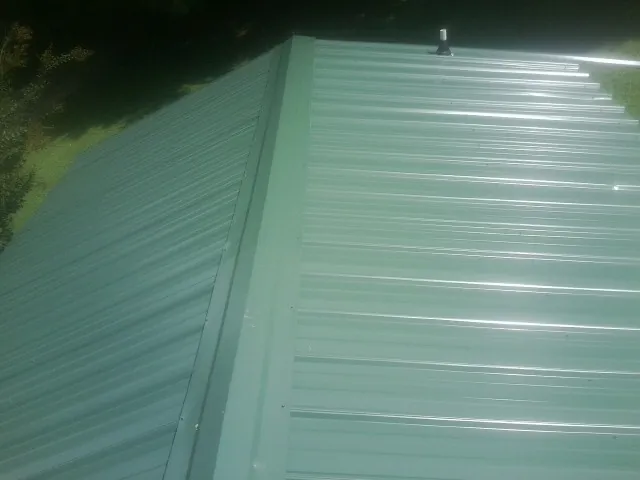 New green metal panels meeting at the ridge of a roof — Flat Roof Repair work by our crew in Mount Pleasant